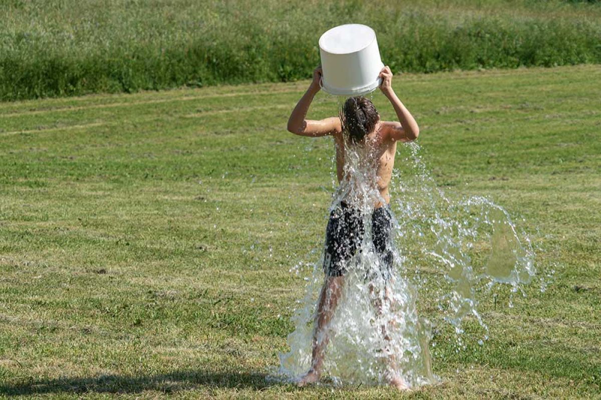 Garçon versant un sceau d'eau sur la tête